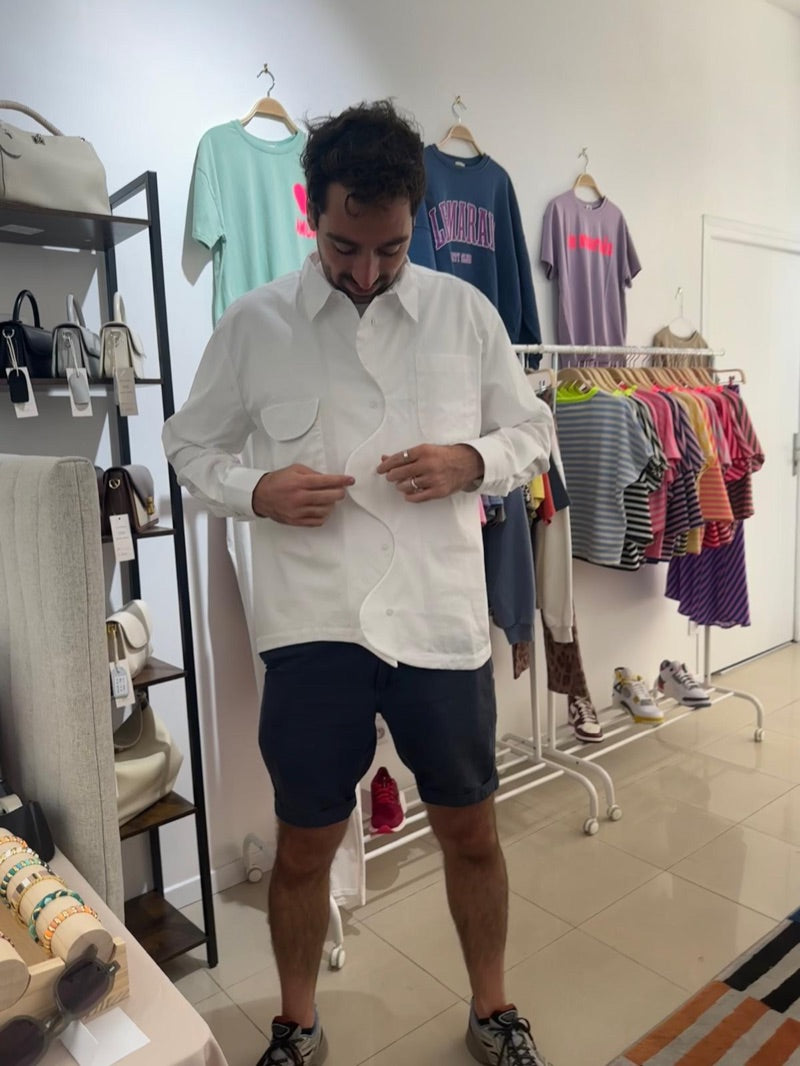 La patte de boutonnage ondulée en train de se fermer, chemise blanche et short bleu marine